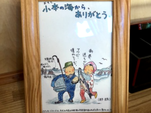 アキサンのイラストが飾られている。浜を背にした漁師の老夫婦のイラストで「小本の海から、ありがとう」のメッセージが描かれている