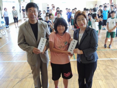 守屋会長から目録をいただいた小本小学校児童代表と小野小本中学校長。
