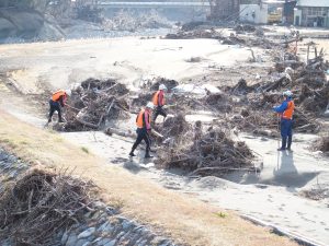 河川敷で手掛かりを探す消防団員たち